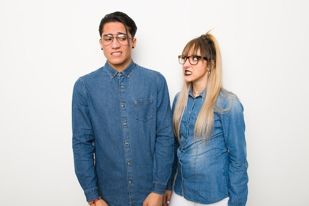 Pareja joven con gafas está un poco nerviosa y asustada apretando los dientes.