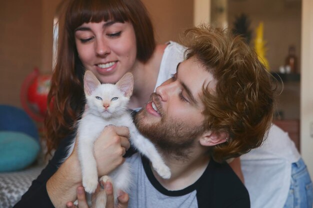 Foto pareja joven con gatito en casa