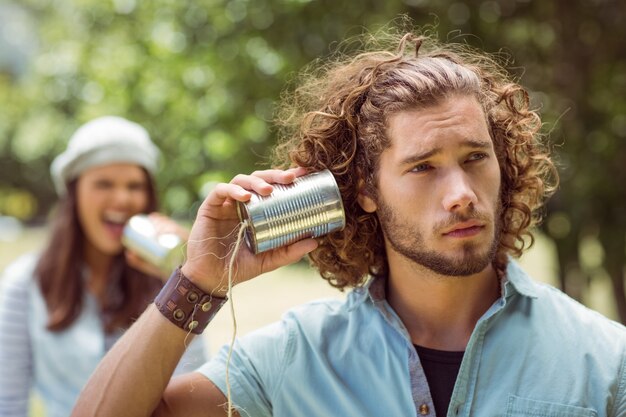 Pareja joven gritando a través de latas