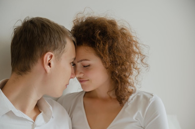 Una pareja joven y guapa sentada en la cama junto con sus narices