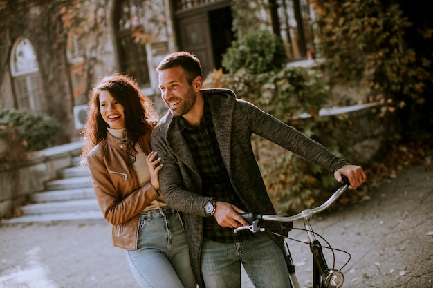 Pareja joven guapo caminando con bicicleta en el parque otoño