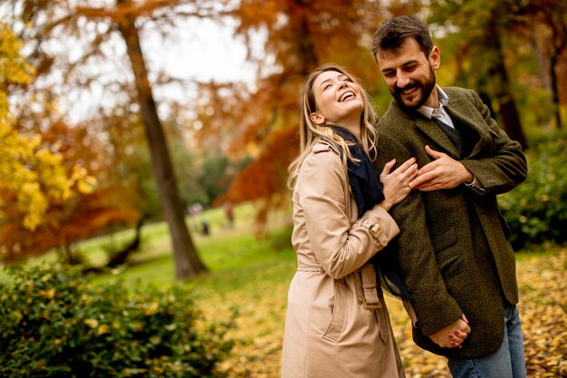 Pareja joven guapo caminando en el parque otoño