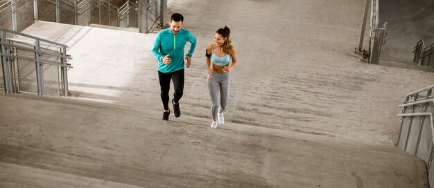 Foto pareja joven guapo corriendo en el entorno urbano