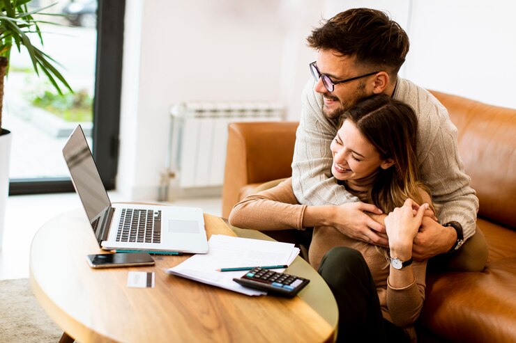 Foto pareja joven guapo usando laptop juntos mientras está sentado en el sofá en casa