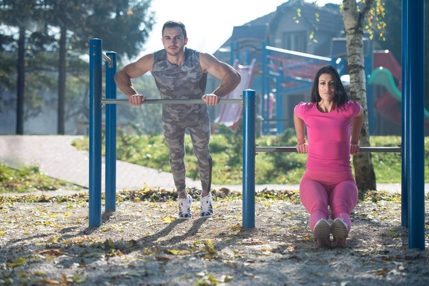 Pareja joven haciendo ejercicio Crossfit con Dips Bar en el área del parque de la ciudad entrenando y ejercitando para el concepto de estilo de vida saludable de resistencia al aire libre