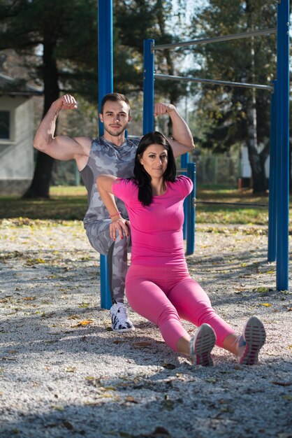 Pareja joven haciendo ejercicio Crossfit con Dips Bar en el área del parque de la ciudad entrenando y ejercitando para el concepto de estilo de vida saludable de resistencia al aire libre