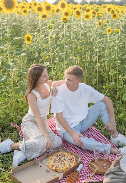 Pareja joven haciendo un picnic en el campo de girasol