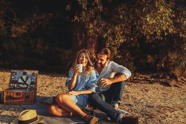 Una pareja joven haciendo un picnic en la playa.