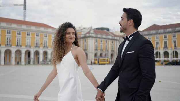 Pareja joven y hermosa caminando por edificios históricos y hablando de acción, hombre de traje y mujer