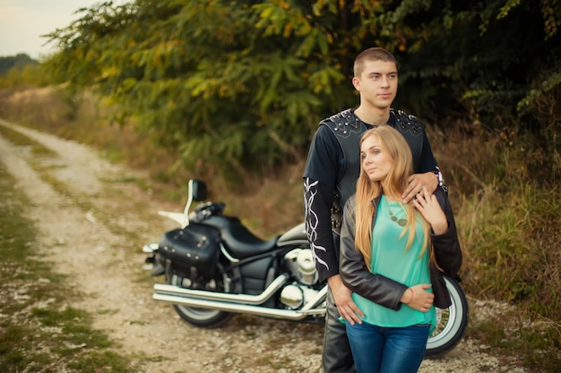 Pareja joven con hermosa moto en carretera.