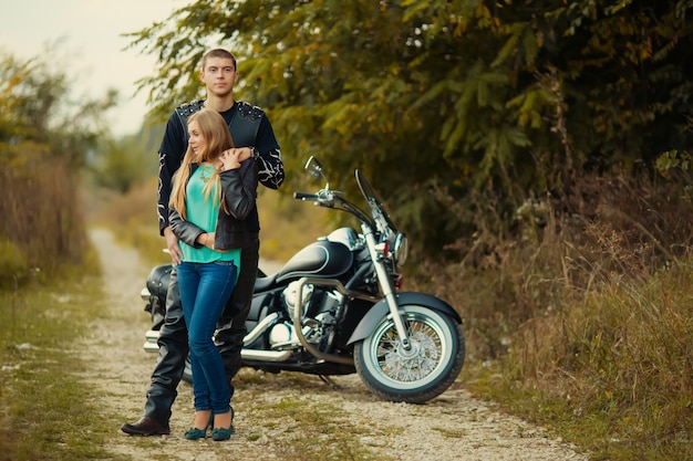 Pareja joven con hermosa motocicleta en carretera.