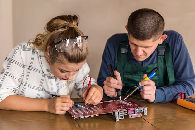 Foto pareja joven de ingenieros reparando dispositivo informático