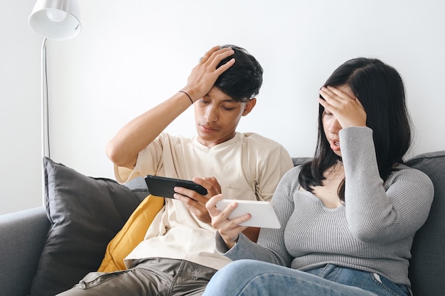 Una pareja joven juega juegos móviles juntos y pierde el juego pasando tiempo juntos en la sala de estar