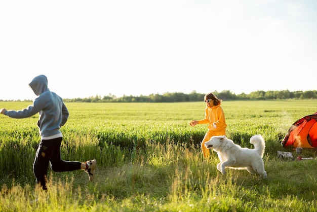 Pareja joven juega con su perro en el camping