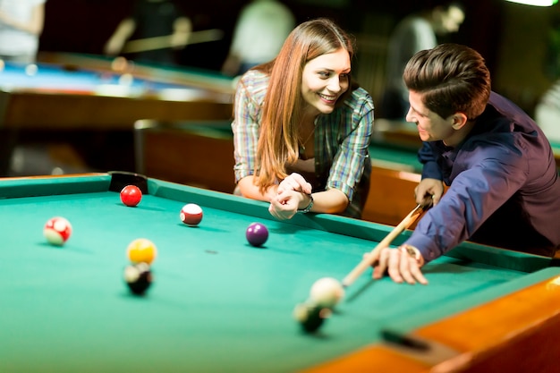 Pareja joven jugando al billar en el bar