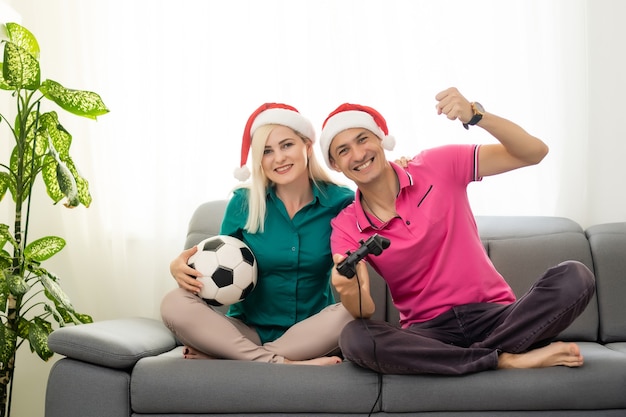 Pareja joven jugando videojuegos con joysticks en casa para Navidad