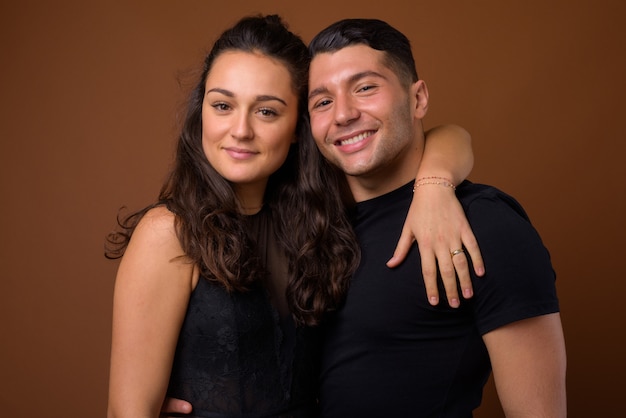 Foto pareja joven juntos y enamorados contra la pared marrón