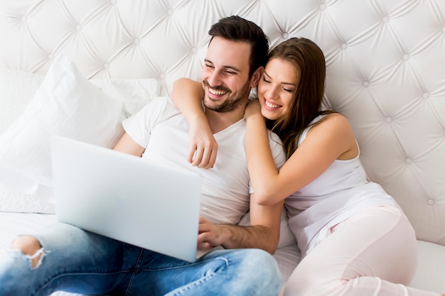 Pareja joven con laptop en la cama