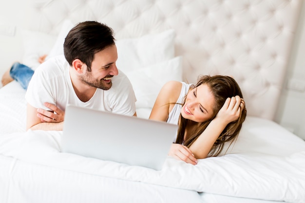 Pareja joven con laptop en la cama