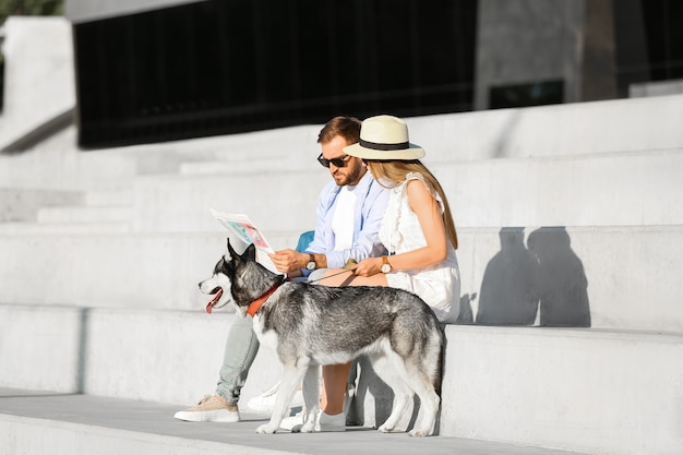 Pareja joven con lindo perro Husky al aire libre