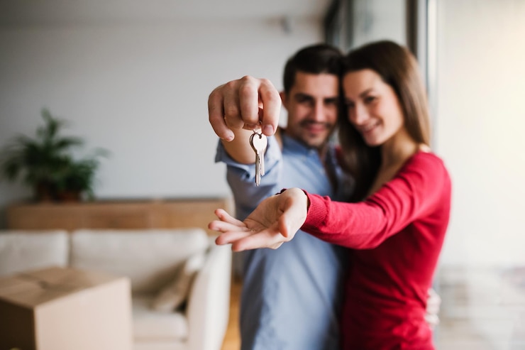 Foto una pareja joven con una llave y cajas de cartón moviéndose a una nueva casa