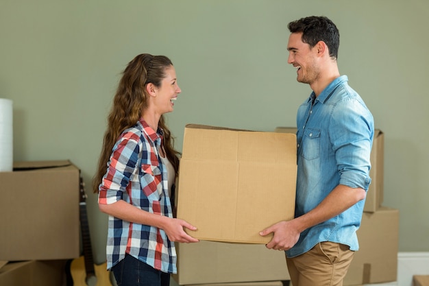 Pareja joven mirando cara a cara mientras desembala cajas de cartón en casa nueva