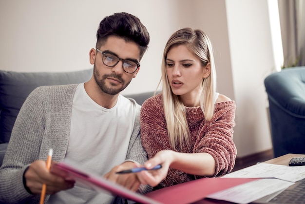 Foto pareja joven moderna pagando facturas en línea desde casa