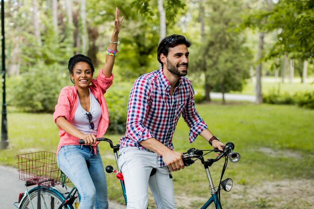 Foto pareja joven montando en la bicicleta tándem