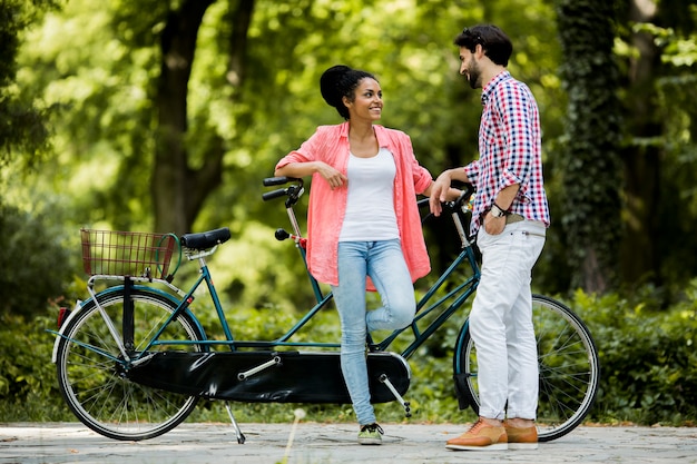 Foto pareja joven montando en la bicicleta tándem