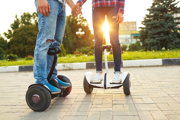 Una pareja joven montando hoverboard scooter eléctrico transporte ecológico personal gyro scooter rueda de equilibrio inteligente