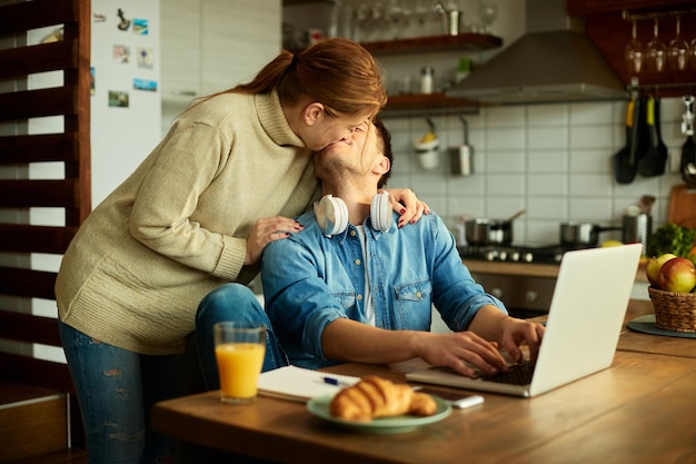 Pareja joven mostrando afecto y besándose en casa