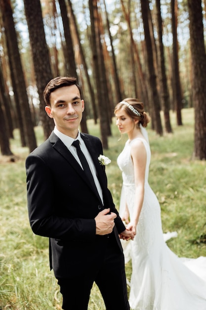 Pareja joven novia y novio están caminando en un paseo por el bosque día de la boda concepto romántico día retrato de recién casados en el amor