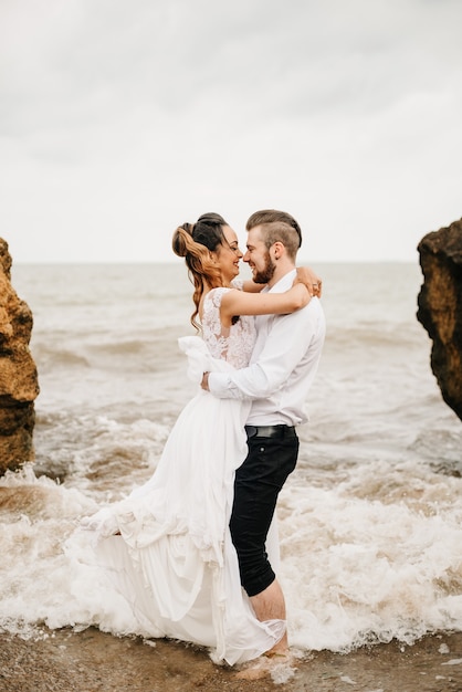 Pareja joven novio con la novia en una playa de arena en un paseo nupcial