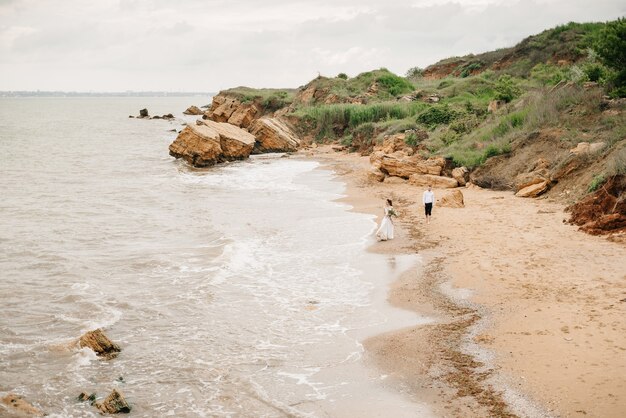 Pareja joven novio con la novia en una playa de arena en un paseo nupcial