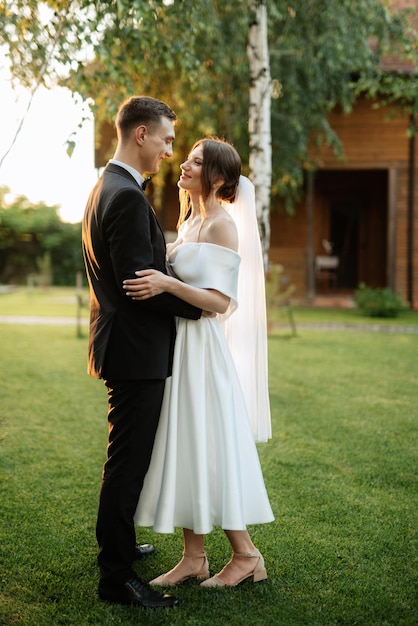 Foto pareja joven el novio con un traje negro y la novia con un vestido corto blanco