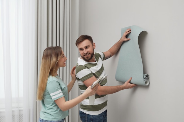 Pareja joven con nuevo papel de pared y paleta de colores en el interior