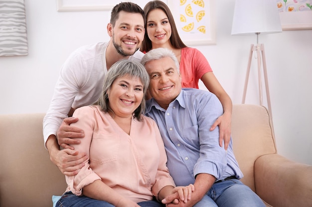 Pareja joven con padres de mediana edad en el sofá de la habitación