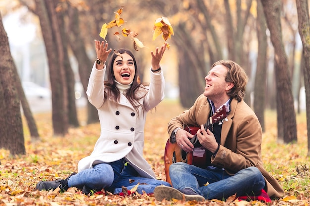 Pareja joven en el parque con guitarra