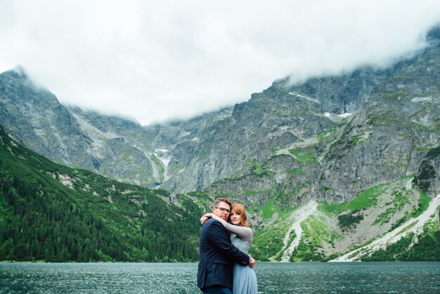 Pareja joven en un paseo cerca del lago rodeado por las montañas de los Cárpatos