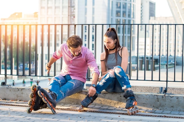 Pareja joven en patines sentado.