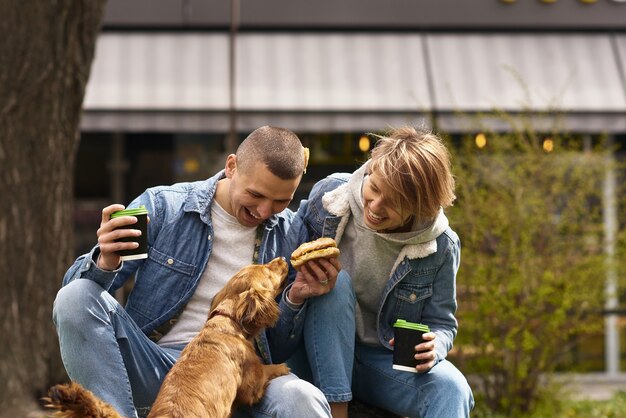 Pareja joven con perro almorzando comida rápida