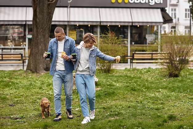 Pareja joven con perro almorzando comida rápida