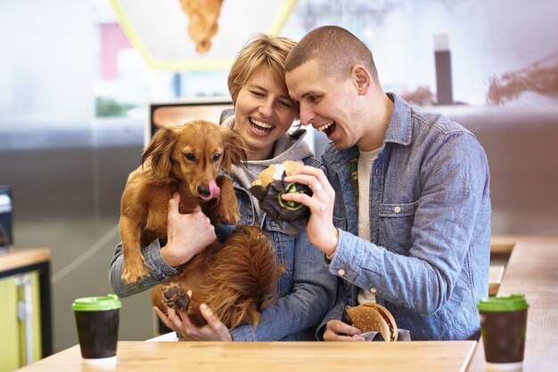 Pareja joven con perro almorzando comida rápida