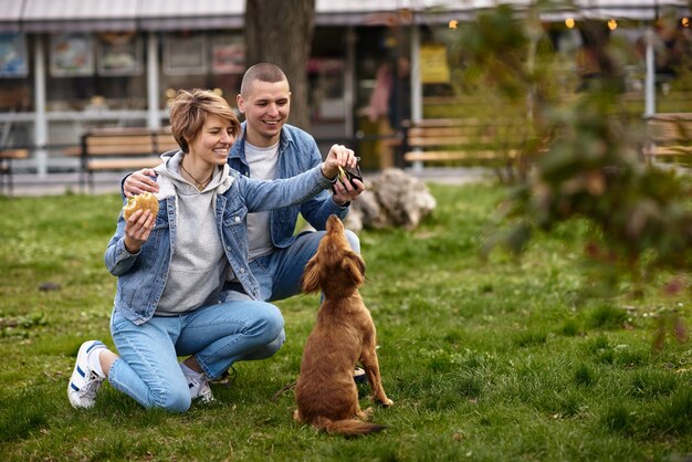 Pareja joven con perro almorzando comida rápida