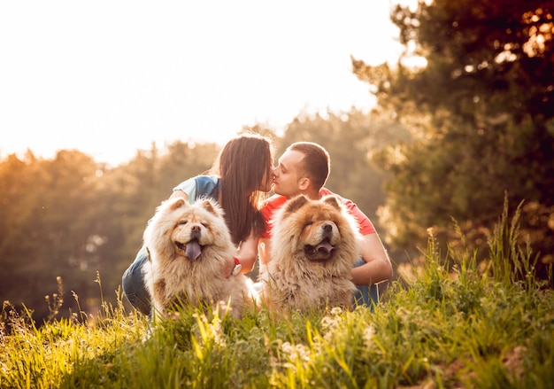 Foto pareja joven con los perros en el parque