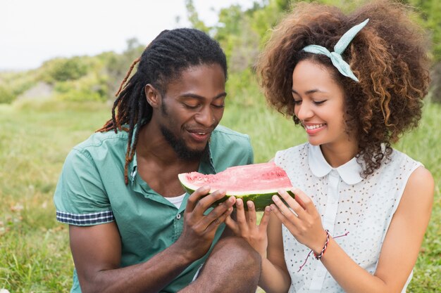 Pareja joven en un picnic comiendo sandía