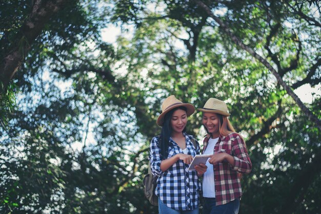 Una pareja joven de pie junto a un árbol contra las plantas