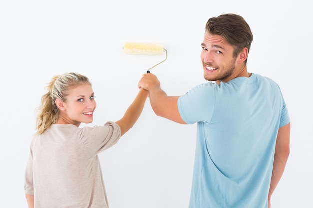 Pareja joven pintando con rodillo