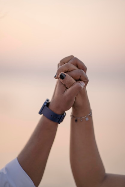 Foto una pareja joven en la playa tomándose de la mano.