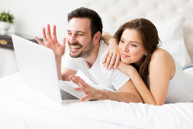 Pareja joven con portátil en la cama